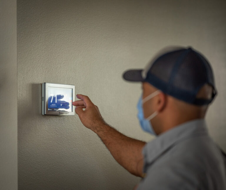 Technician adjusting thermostat