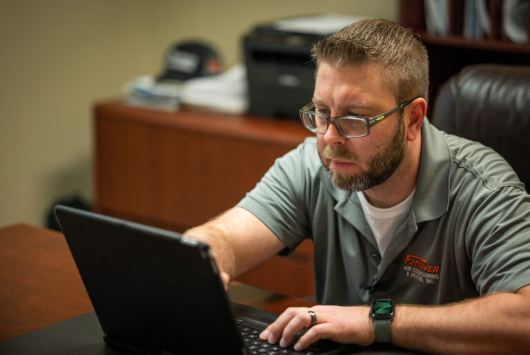 Technician working on laptop in office